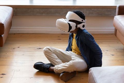 African American boy exploring virtual world at home using white VR headset