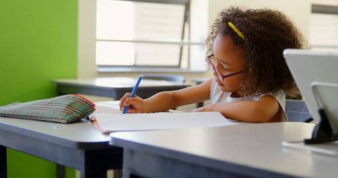 Focused Schoolgirl Writing in Classroom Seat with Dedication - Download Free Stock Images Pikwizard.com