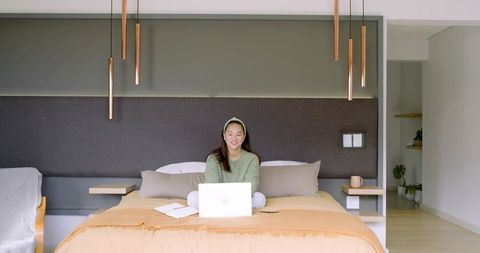 Relaxed woman using laptop on comfortable bed