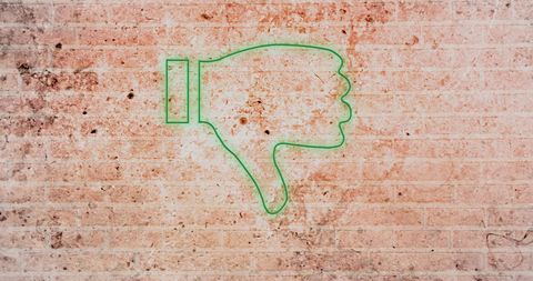 Neon thumbs down symbol on weathered brick wall background