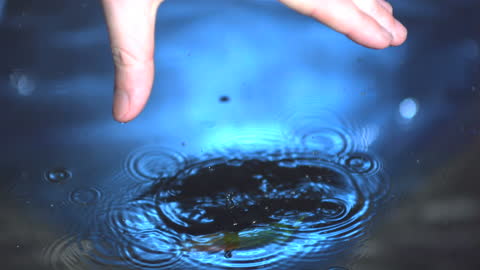 Hand Dropping Jalapeno Pepper into Water Creating Ripples