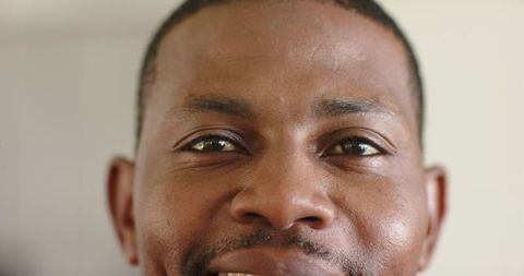 African american mid adult man smiling, looking at camera closeup headshot neutral backdrop