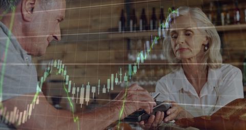 Senior man tapping credit card amid stock market graphs