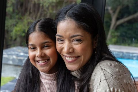Mother and daughter smiling by pool in cozy knitwear, natural light family portrait