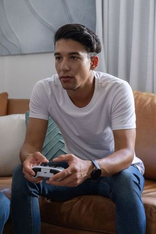 Focused african american gamer playing console controller on couch in cozy living room