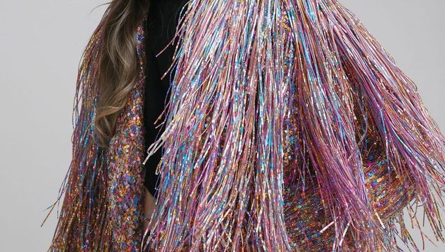 Model wearing iridescent metallic fringe jacket sparkling with multicolor tinsel