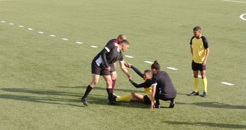 Soccer Players Assisting Injured Teammate on Field