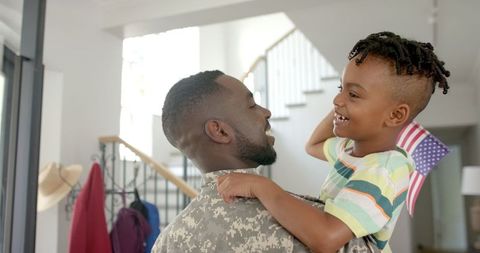African American Father in Military Uniform Embracing Son Holding American Flag