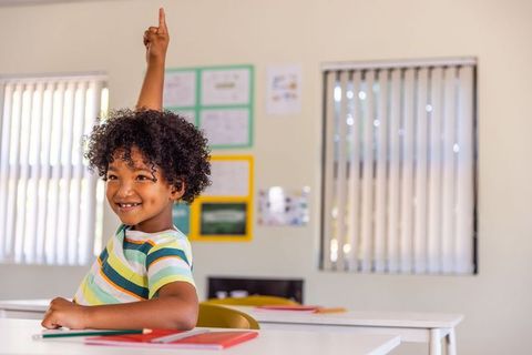 African american student raising hand in classroom smiling and engaging in learning