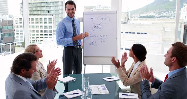 Business team is applauding male colleague after his presentation on strategy planning in a modern office. The image can be used for representing corporate success, teamwork, business meetings, and productivity in a professional environment. Ideal for use in business presentations, corporate websites, and training materials.