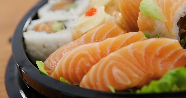 A close-up view of a sushi platter featuring fresh salmon sashimi and sushi rolls, with copy space. The vibrant colors and presentation suggest a delicious meal for those who enjoy Japanese cuisine.