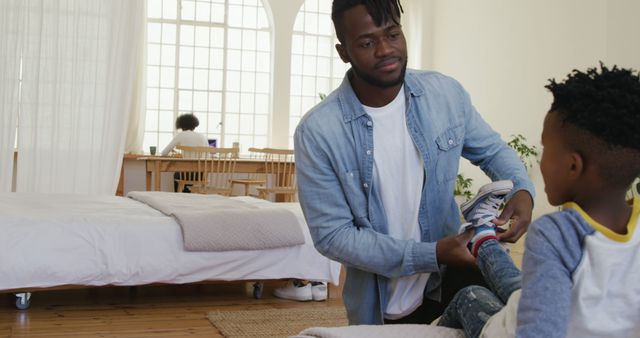 Father tying son's shoes at home with daughter studying in background - Download Free Stock Images Pikwizard.com