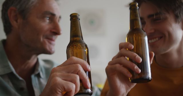 Happy senior caucasian father and adult son drinking a toast with bottles of beer together - Download Free Stock Photos Pikwizard.com