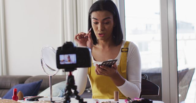 Beauty vlogger demonstrating a makeup tutorial, recorded in a modern home environment. Ideal for articles and blog posts on beauty tips, makeup tutorials, how to become a beauty influencer. Suitable for social media campaigns, beauty and lifestyle content, and influencer marketing strategies.