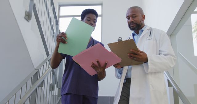 African american male and female doctors holding clipboard and talking at hospital. Medicine, healthcare, lifestyle and hospital concept.
