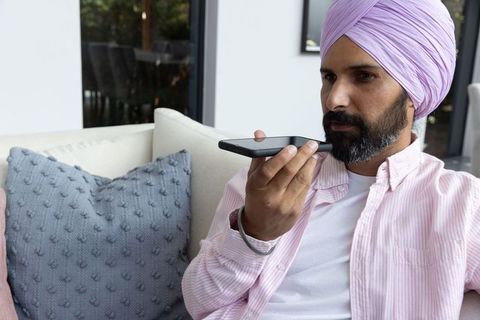 Man in Turban Using Smartphone Voice Assistant on Sofa