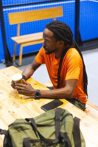 Man Relaxing with Coffee in Gym Lobby After Workout