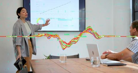 Presenting business leader pointing at analytics screen with growth charts in boardroom