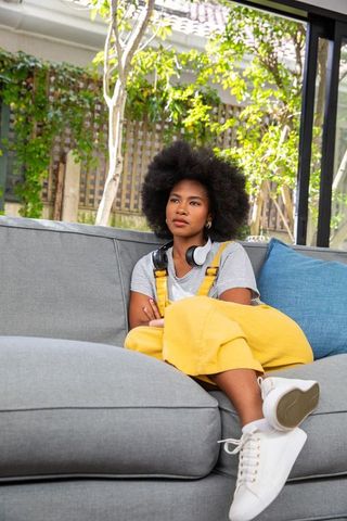 Relaxing at Home: Woman in Yellow Overalls with Headphones