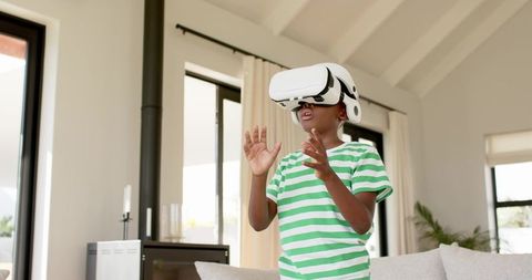 Young boy exploring virtual reality with headset in modern sunlit living room
