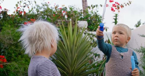 Young siblings enjoying bubble play in lush garden