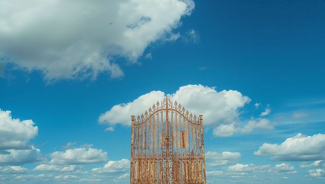 Ornate rusted iron gate against expansive sky