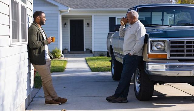 Multigenerational morning coffee chatting on suburban driveway with pickup truck