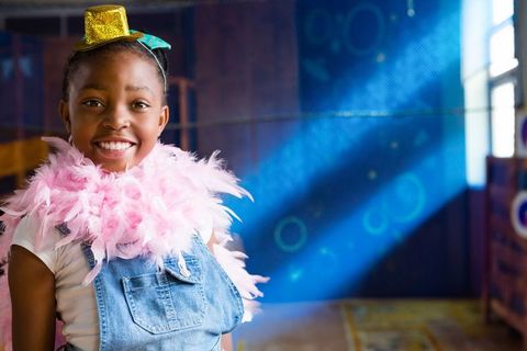 Joyful girl in costume boasting pink feather boa and sparkly hat