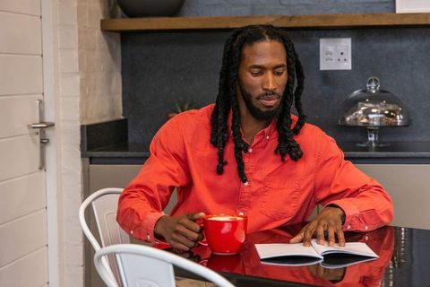 African american man sipping coffee and journaling at minimalist kitchen table
