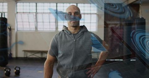 Athletic man posing in industrial gym with kettlebells and augmented reality overlays