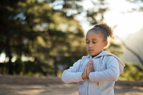 School-age Girl Practicing Mindfulness in Sunlit Forest Clearing
