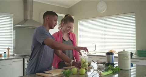 Diverse Couple Preparing Green Smoothie in Bright Modern Kitchen for Healthy Lifestyle