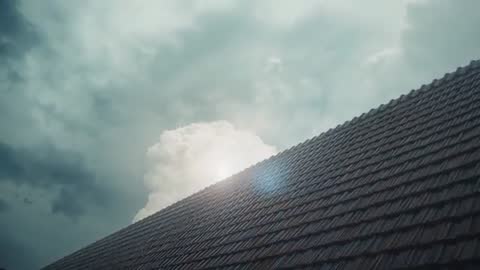 Sun Gleaming Over Tiled Roof with Cumulus Clouds