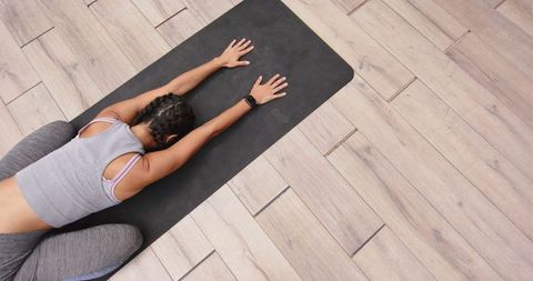 Woman practicing child's pose on yoga mat for relaxation and flexibility