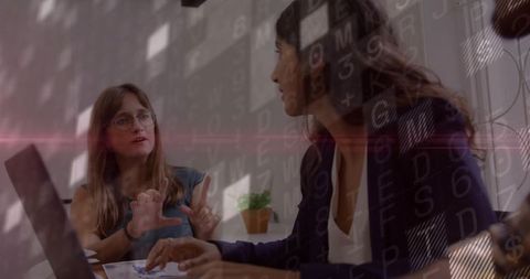 Professional women discussing with digital code overlay in modern office