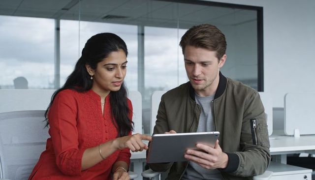 Colleagues collaborating over tablet in modern office discussing data and strategy