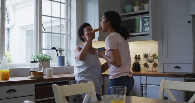 Mother and daughter enjoying breakfast time together in a brightly lit, cozy kitchen. They are showing love and connection while sharing food. Ideal for content about family life, morning routines, home, and parenting.
