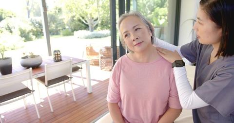 Caregiver comforting senior woman with shoulder touch during outdoor home care visit