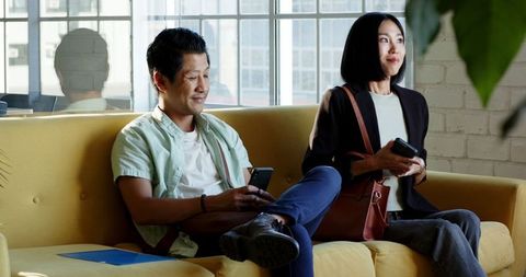 Diverse Colleagues Engaged in Business Brainstorm Session on Yellow Couch