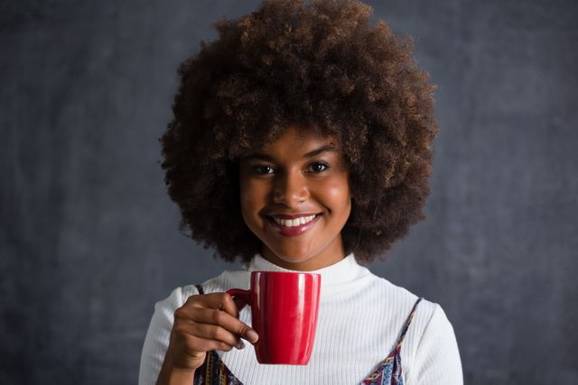 This image can be used for promoting coffee brands, lifestyle blogs, and wellness articles. It is ideal for advertisements focusing on relaxation, positivity, and everyday enjoyment. The cheerful expression and casual setting make it suitable for social media posts and personal development content.