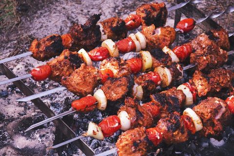 Grilling Spicy Shish Kebabs with Cherry Tomatoes and Onions over Charcoal