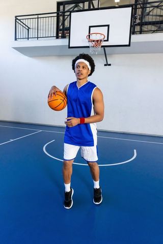 Young Basketball Player Holding Ball on Indoor Court