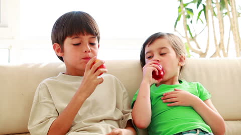 Siblings Enjoying Fresh Red Apples Indoors