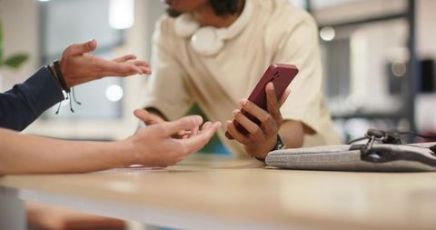 African american colleagues collaborating over smartphone in modern coworking lounge