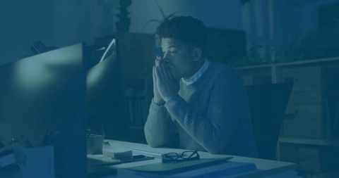 Focused Mid-Adult Man Working Late at Office with Monitors