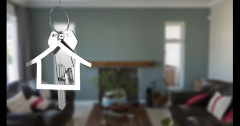House-shaped keyring with keys in modern living room interior