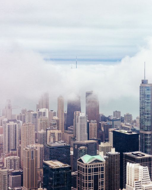 Iconic city skyscrapers enveloped in morning fog, offering a captivating view of modern urban architecture. Ideal for illustrating themes of urban development, corporate growth, weather changes, or travel destinations. Useful for blogs, websites, backgrounds, or marketing materials focusing on business, innovation, and city life.
