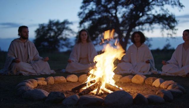 Meditating circle around campfire at dusk for mindfulness retreat and ritual practice