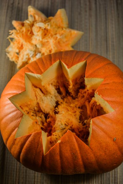 Freshly carved pumpkin with top removed and inner fibrous material exposed, perfect for Halloween decorations, fall themed projects and seasonal recipes. Useful for illustrating DIY pumpkin carving steps or promoting autumn festivities.