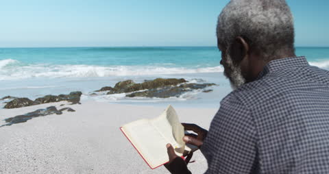 Senior Man Relaxing with Book by Tranquil Ocean